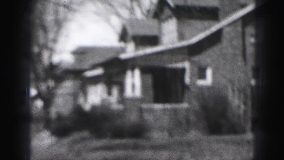 1946 Harrisburg home-movie frame showing a modest house exterior, porch, yard, and bare trees in soft 8mm focus.