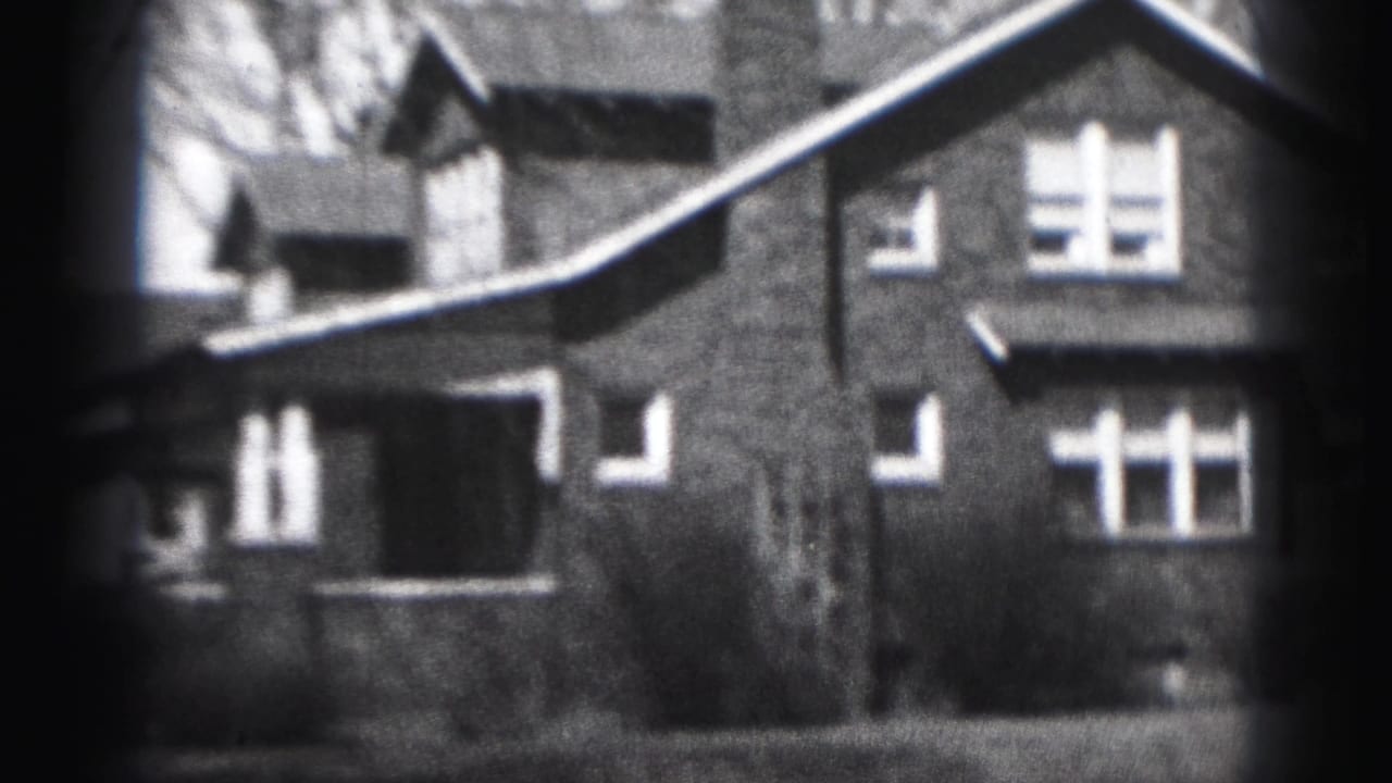 Closer street-side view of the brick house facade with windows and rooflines.