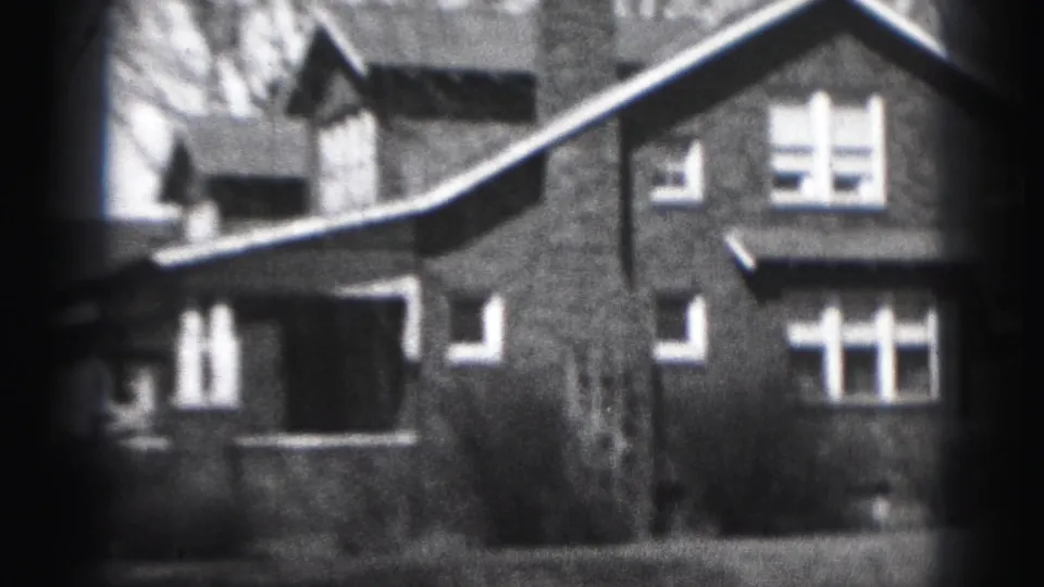 1946 Harrisburg frame showing the brick house facade, divided windows, roof eaves, and leafless trees in black-and-white 8mm.