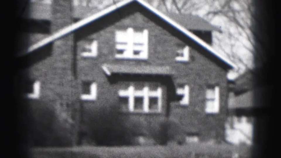 1946 Harrisburg home-movie view of a brick house facade with steep gable roof, chimney, and white-trimmed windows.