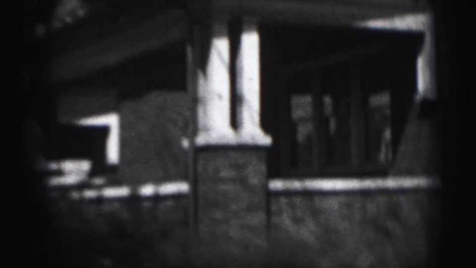 Close exterior view of the Harrisburg house porch, showing a brick column, covered entry, steps, and shadowed front door.