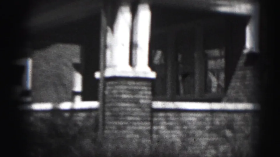 Black-and-white 8mm view of the house porch area in Harrisburg, with a brick support column, low wall, and recessed entry.