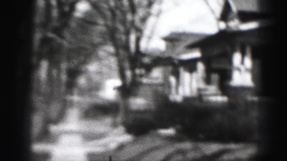 A soft 8mm view of a Harrisburg residential block in 1946, with sidewalks, bare trees, and modest house fronts.