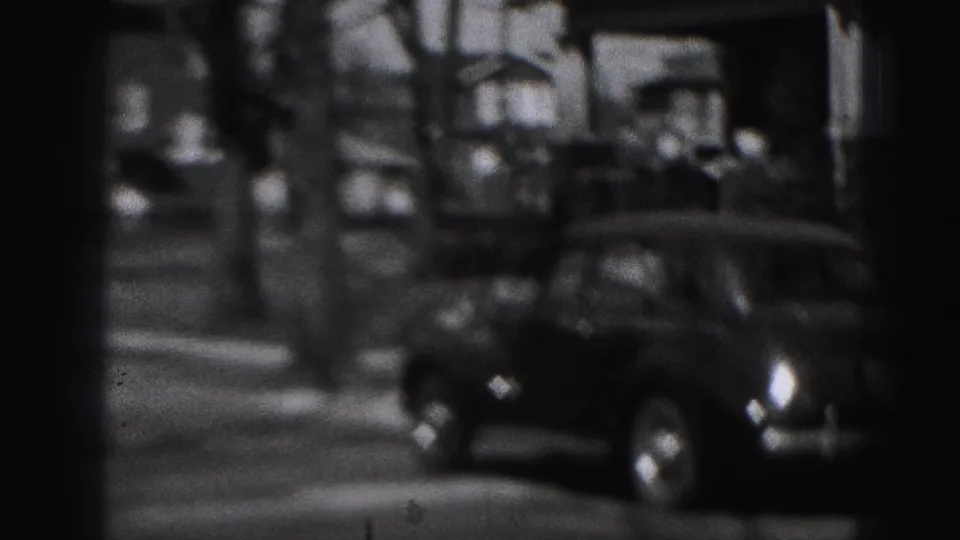 Black-and-white 1946 Harrisburg street view with a parked automobile, residential houses, trees, and distant people.