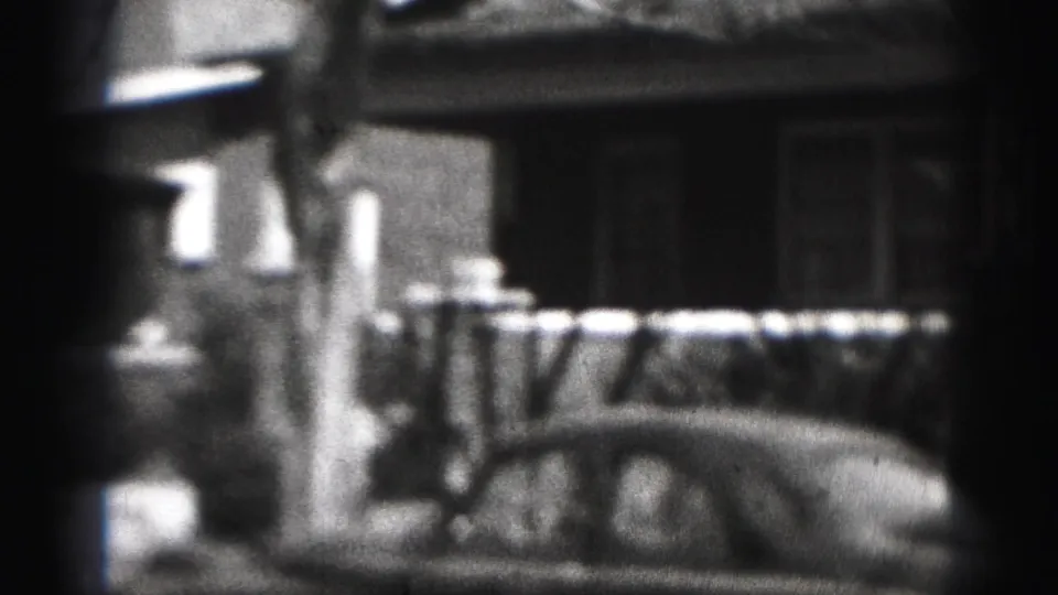 Harrisburg residential house frontage with porch railing, sidewalk area, and part of a parked car in a 1946 home-movie frame.