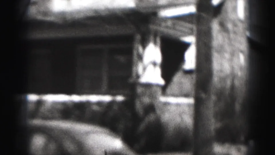 1946 Harrisburg frame showing a house front, porch railing, tree trunk, parked car edge, and a briefly visible person near the building.