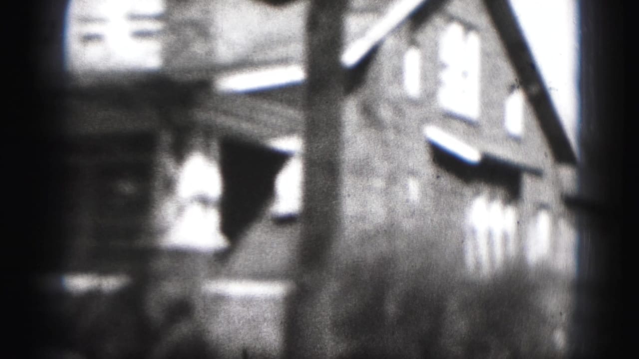 1946 Harrisburg home-movie frame showing a large multi-story house with bright windows and heavy 8mm vignetting.