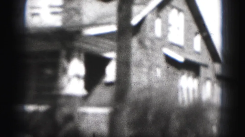 1946 Harrisburg home-movie frame showing a large multi-story house with bright windows and heavy 8mm vignetting.