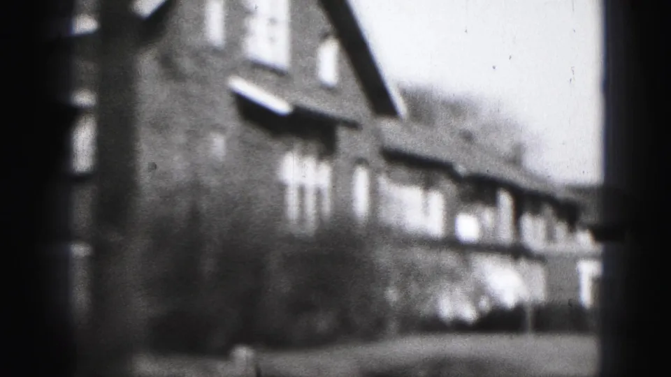 Black-and-white 1940s Harrisburg view of a large house exterior, framed by dark edges and soft home-movie focus.