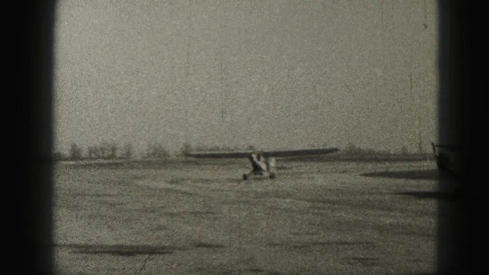 A small propeller aircraft taxis on a rural Harrisburg, Pennsylvania airfield in 1946 home-movie footage, with soft focus and dark film borders.