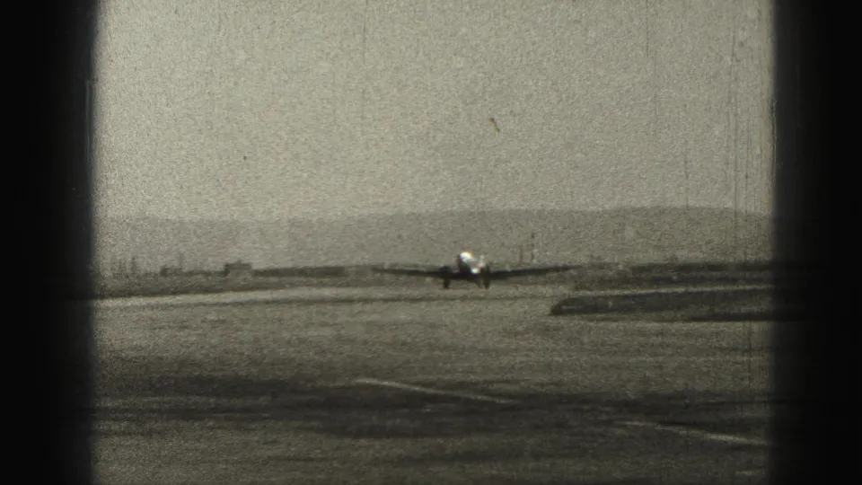 Distant 1946 Harrisburg airfield view of a small aircraft taxiing along the runway under an open sky.