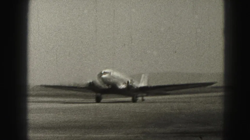 The aircraft continues forward on the Harrisburg air strip in 1946, seen through soft, grainy 8mm home-movie texture.