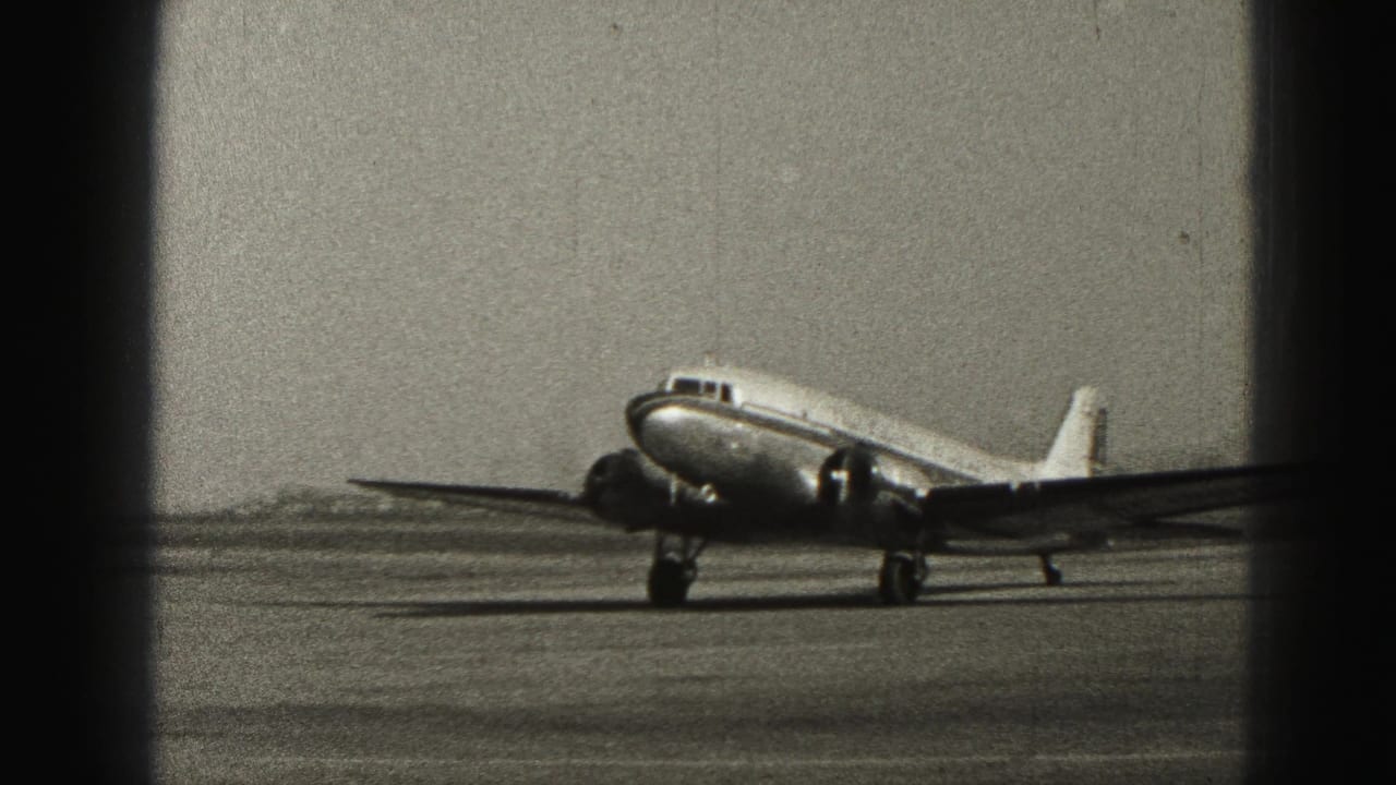 Propeller airplane seen from the front quarter as it moves along the runway.