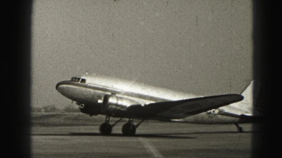 Twin-engine propeller airplane in side view on a Harrisburg runway, captured on 8mm home-movie film in 1946.