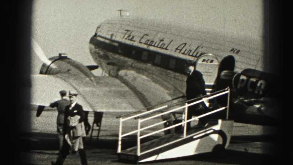 People in period coats and hats move around the mobile stairs beside the Capital Airlines DC-3 on the Harrisburg airfield.