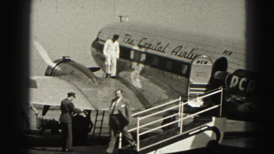 A suited man walks across the apron while passengers and ground staff remain beside the Capital Airlines aircraft in Harrisburg.