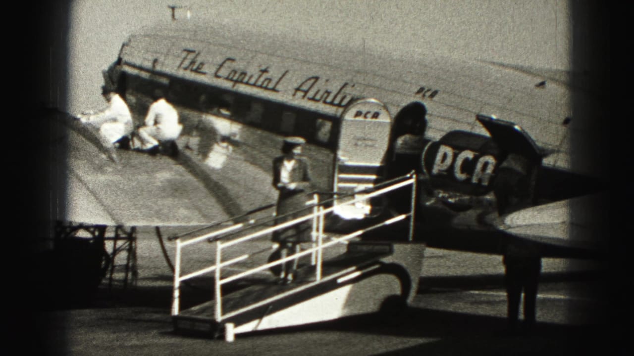 A uniformed attendant stands by boarding stairs beside the marked DC-3 aircraft.