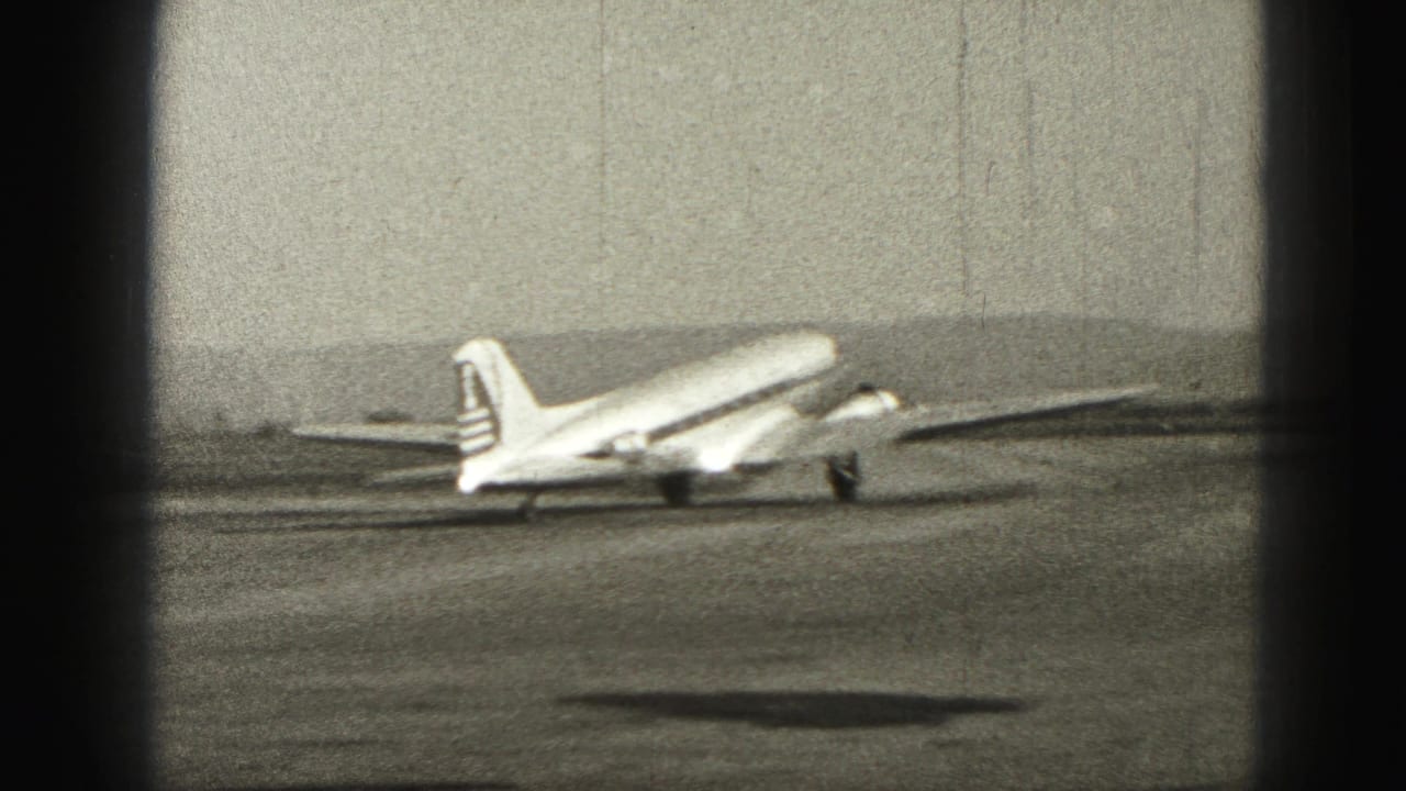 Propeller passenger plane on a runway with hills in the background.