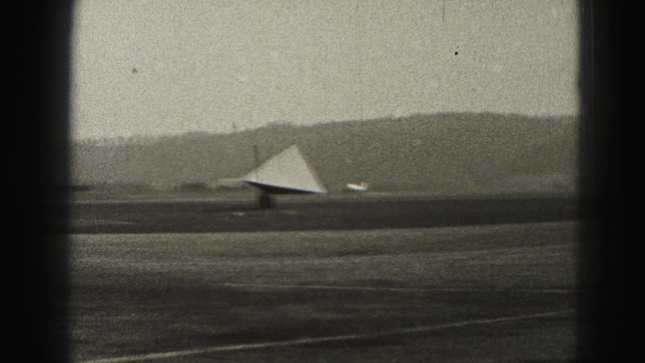 Distant runway view with a triangular light-toned structure near the airfield.