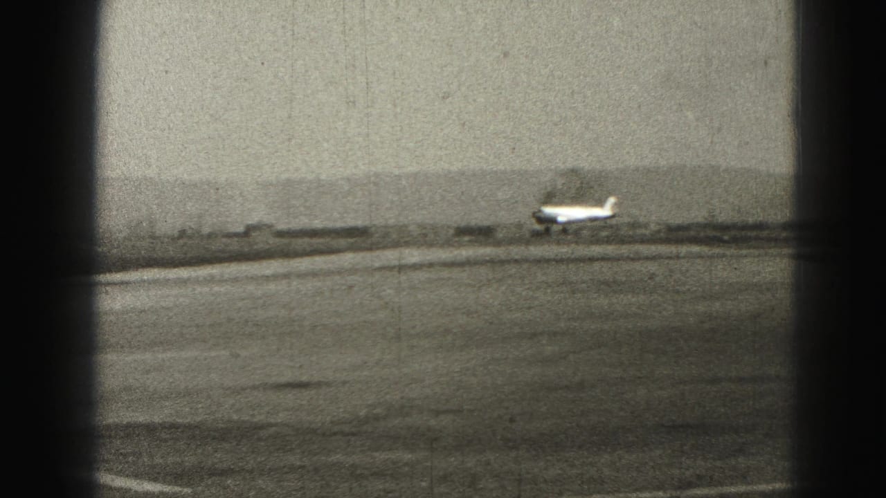 Small airplane moving along the runway with distant hills behind it.