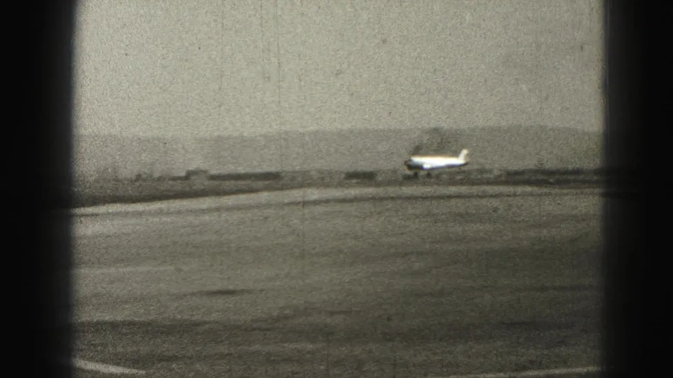 Small propeller airplane continuing down a Harrisburg runway in grainy black-and-white 8mm footage from 1946.