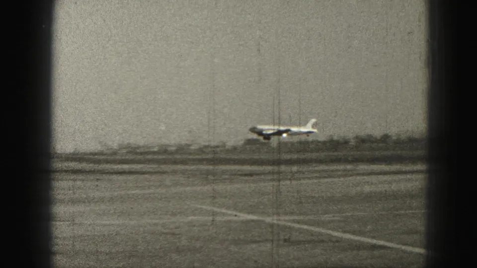 Small aircraft airborne over the runway in Harrisburg, framed by dark 8mm edge shadows and a hazy 1946 airfield background.