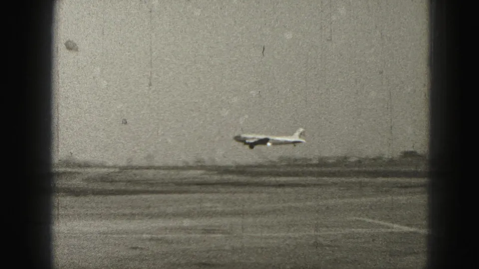 1946 Harrisburg-area 8mm frame showing a commercial airplane touching down on a runway with a low horizon and heavy frame-edge shadows.