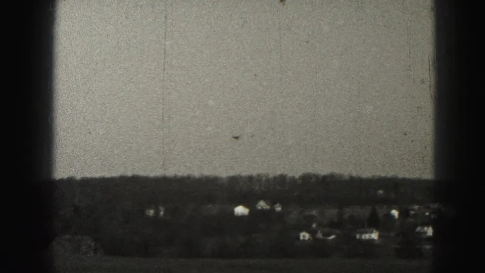 Harrisburg-area suburban landscape in 1946, with distant houses and a tree line viewed through dark 8mm frame borders.