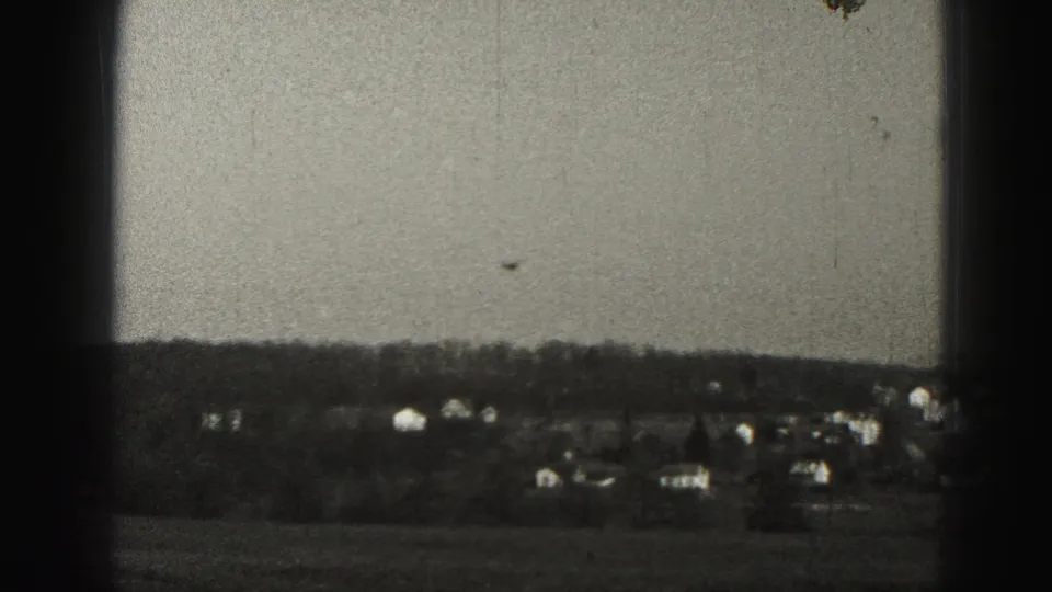 Small aircraft flying low over a Harrisburg-area suburban landscape, with scattered houses, fields, and trees visible below.