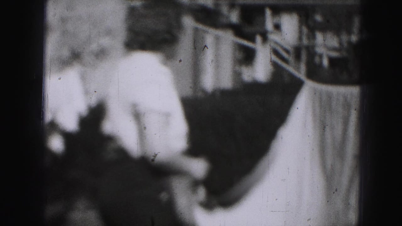 Woman turns near a clothesline while a large sheet hangs beside her.