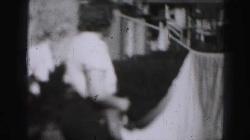 The woman appears near a backyard clothesline in Harrisburg, with a sheet draped across the frame and house details behind her.