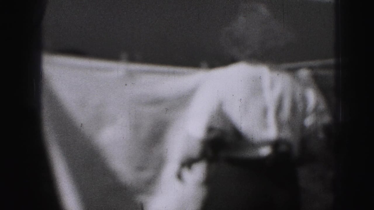 Large sheet hanging on a clothesline with a partially visible person at the right edge.