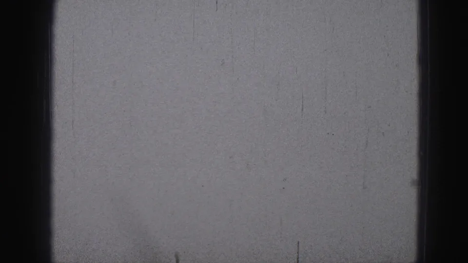 The frame is largely obscured by gray exposure or leader-like film material, with scratches, dust, and dark edge marks visible.