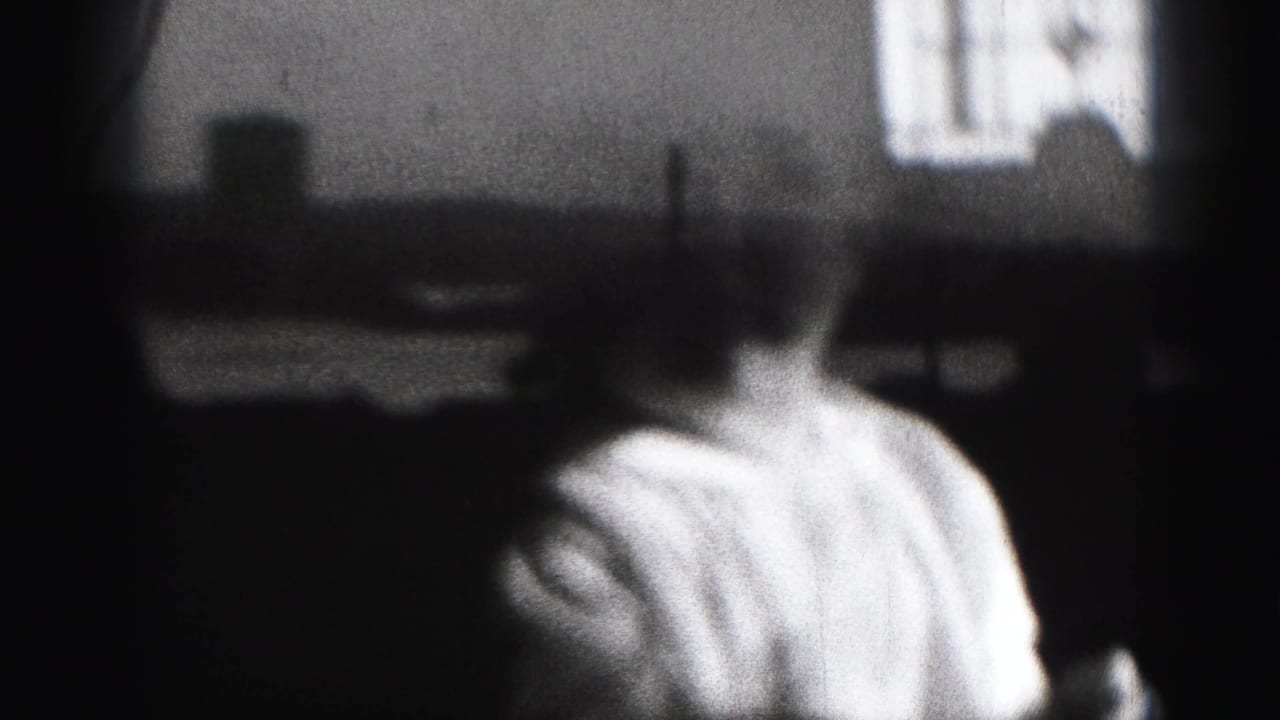 1946 Harrisburg home-movie frame showing a baby in a light shirt seen close up in a shadowed interior with a bright window behind.