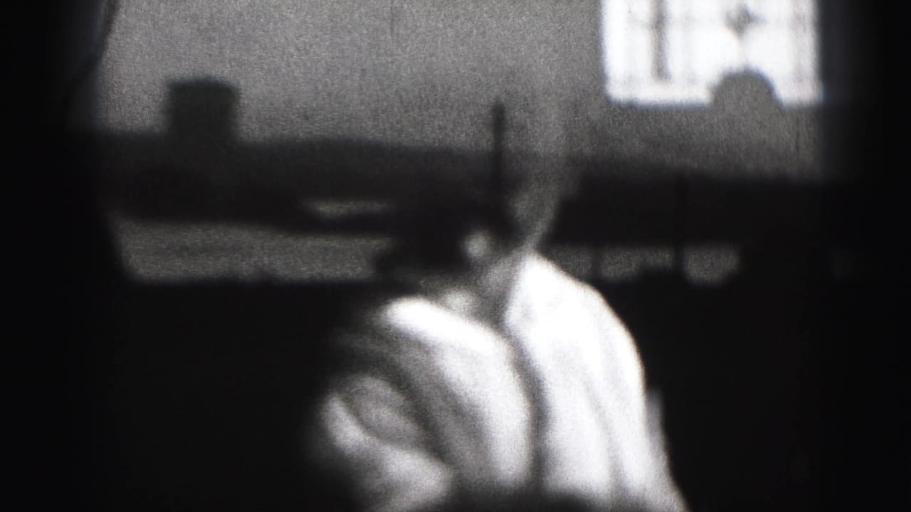 Baby in a light shirt turns slightly in a dark indoor space with a window behind.