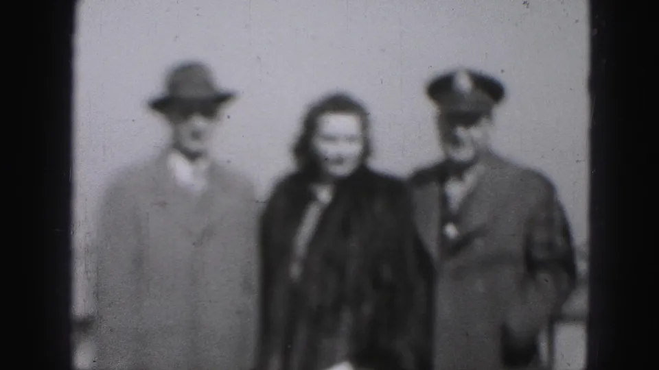 In 1946 Harrisburg home-movie footage, a woman stands between two formally dressed men, including one wearing a peaked cap.