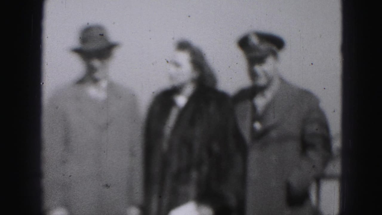 Soft black-and-white 1946 Harrisburg frame showing a woman walking between a fedora-wearing man and a man in a peaked cap.