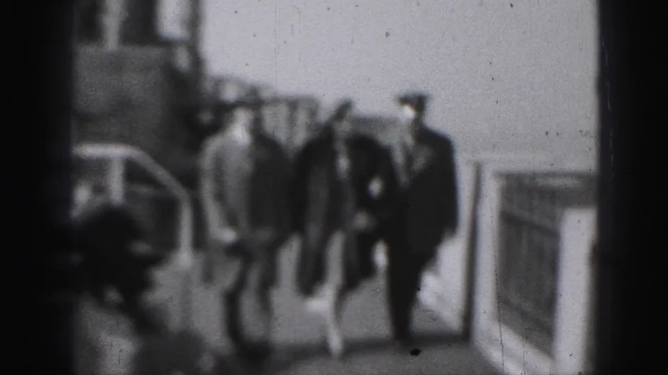 In a soft 1946 Harrisburg 8mm frame, a couple and a uniformed police officer walk toward the camera along a railed walkway.