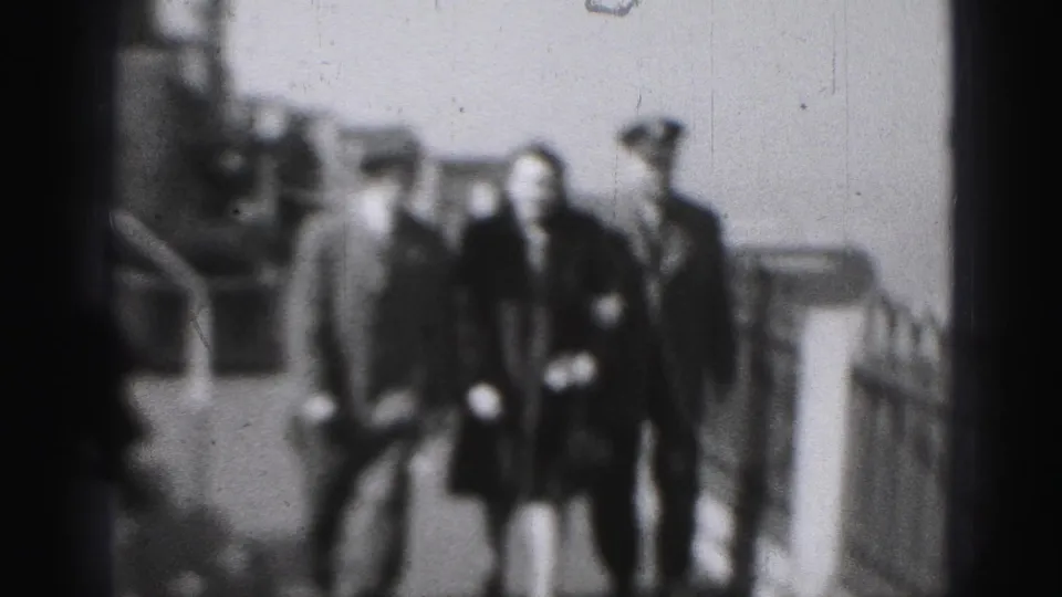 The group moves closer in the 1946 Harrisburg home-movie frame, with the woman centered between the officer and a hatted man.