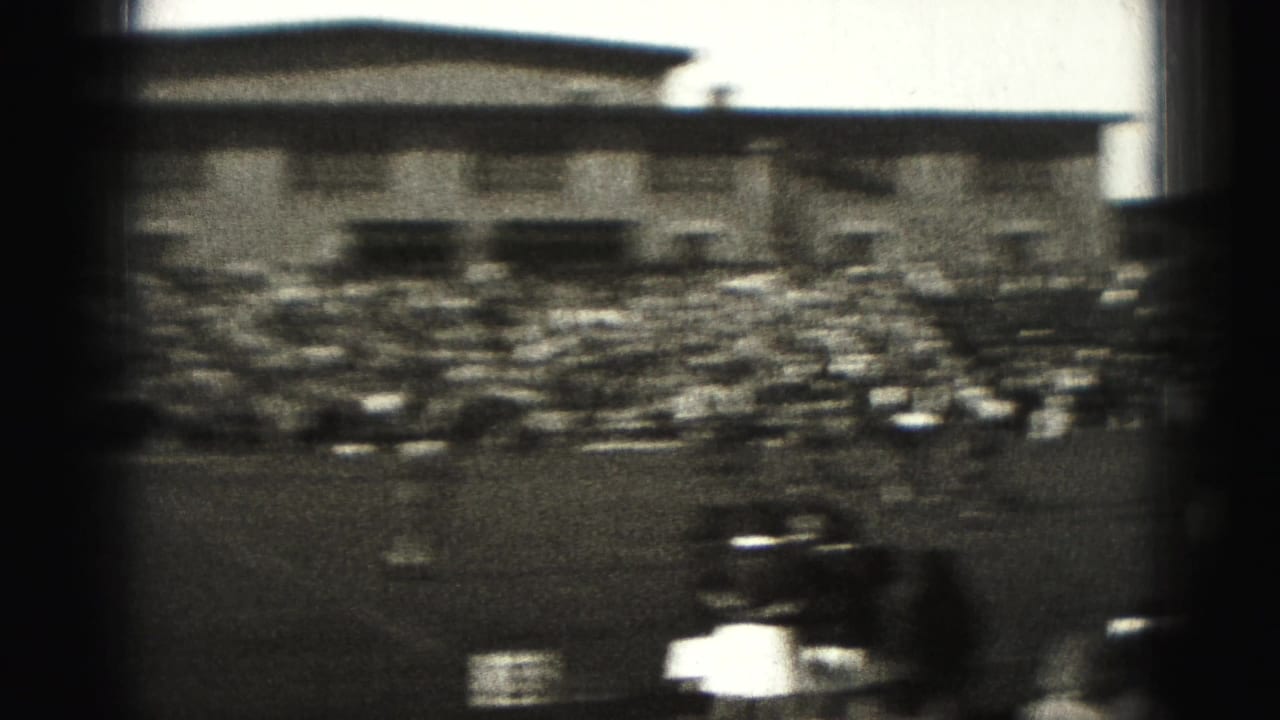 Harrisburg, Pennsylvania 1946 home-movie frame showing a distant field match, sideline crowd, bleachers, and soft 8mm blur.