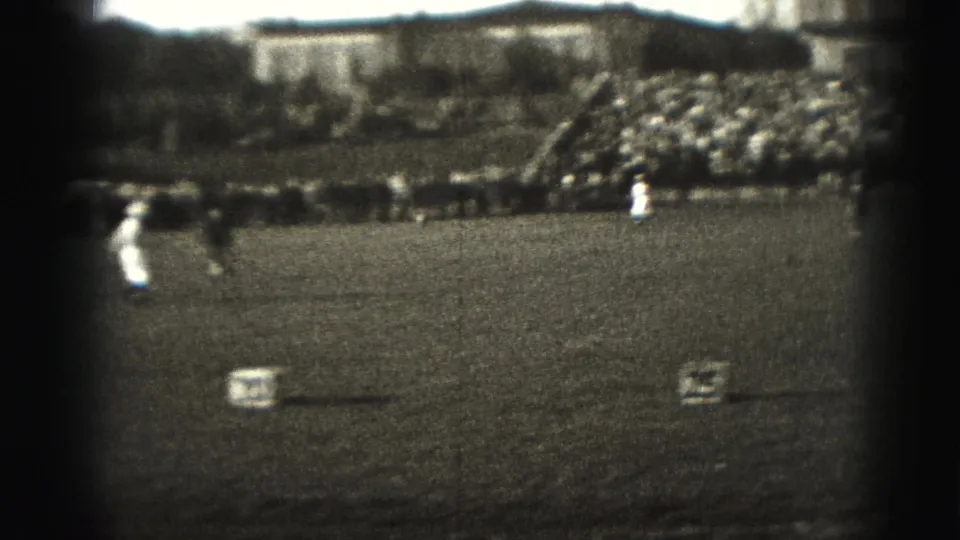 Wide 1946 Harrisburg sports frame with players on a grass field, numbered markers, sideline spectators, and crowded bleachers.