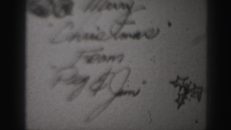 1946 Harrisburg 8mm frame showing blurred cursive writing on paper with a small dark printed or drawn mark near the right edge.