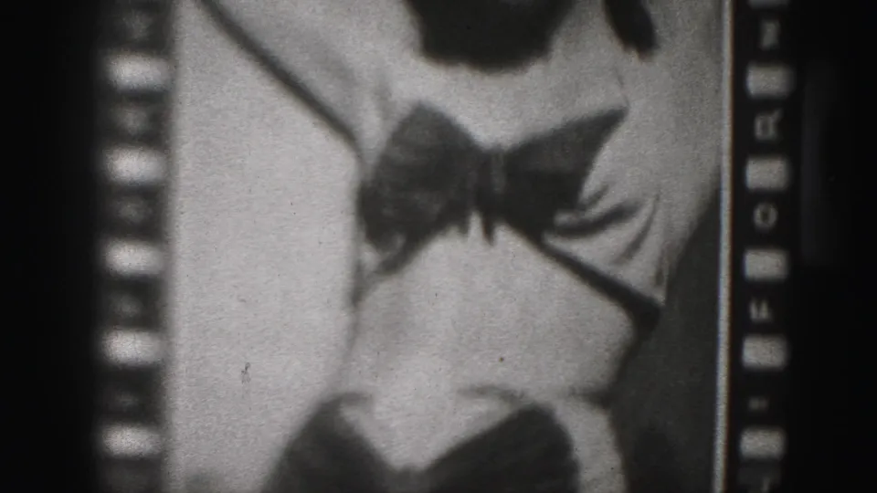 1946 Harrisburg home-movie frame focused on a woman's bow-front garment, lower torso, and legs, with 8mm sprocket edges visible.