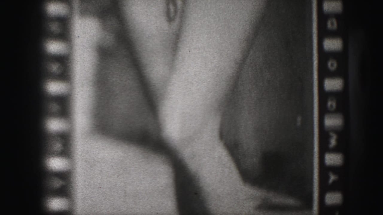 Soft black-and-white film frame showing part of a poster with a woman's legs and high heels.