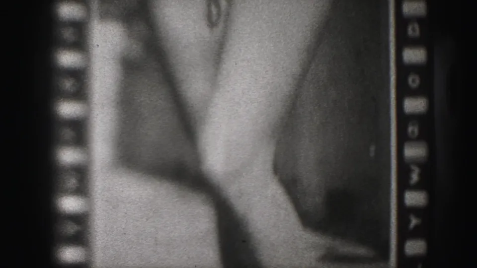 Harrisburg 1946 8mm frame showing a grainy poster detail with a woman's legs and high heels beside visible sprocket edges.