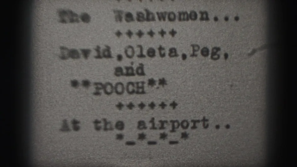 1946 Harrisburg 8mm frame with a blurred typewritten title card for The Washwomen and cast-name text on grainy film.