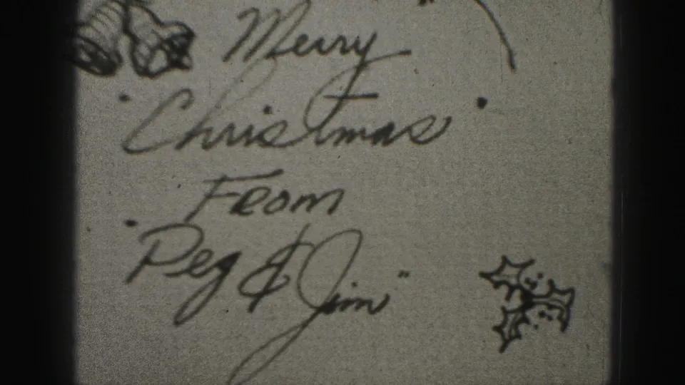 Close-up of a handwritten Christmas card reading Merry Christmas from Peg and Jim, with small holiday drawings visible on aged paper.
