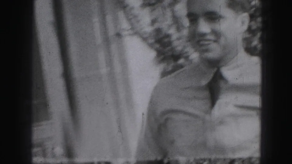 In 1946 Harrisburg home-movie footage, a man in a light shirt and tie appears close to the camera beside a residential exterior.