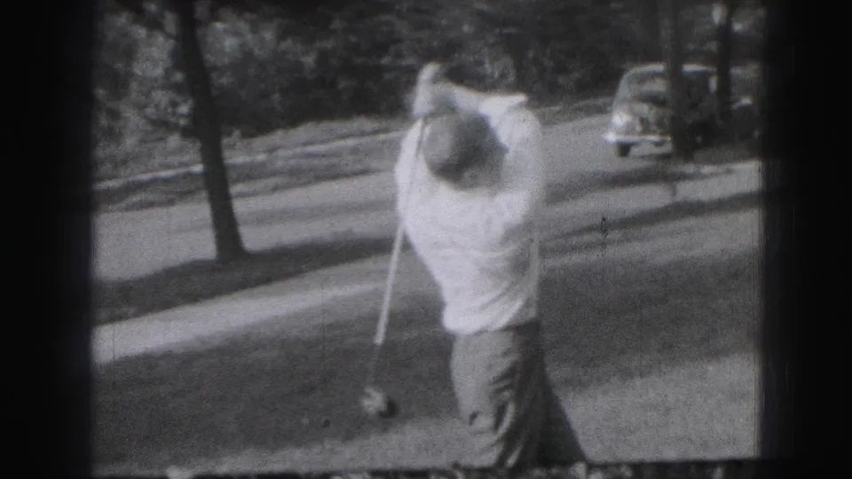 A man follows through on a golf swing in a suburban Harrisburg setting, with a car and tree-lined street visible in the 1946 frame.