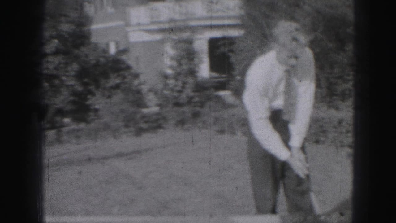 In 1946 Harrisburg home-movie footage, a man in a white shirt and tie prepares a golf swing on a grassy residential lawn.